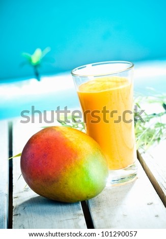 Creamy mango smoothie with blended fresh mango juice and yoghurt served overlooking a tropical ocean