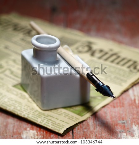 Old Ink Quill and an antique newspaper on an ancient wooden background