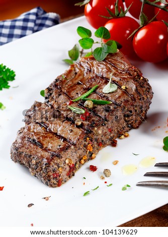 Thick portion of succulent tender peppered steak grilled to perfection and served on a plate with fresh herbs and tomatoes