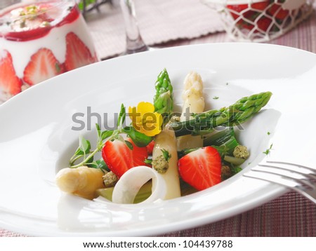 Healthy strawberry and asparagus salad with succulent green and white asparagus tips and sliced ripe red strawberries served in a white dish