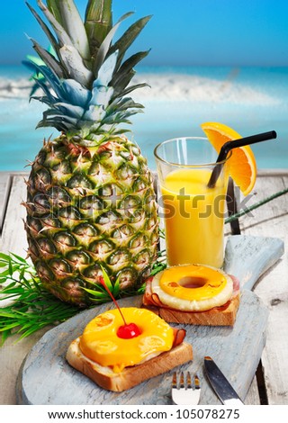 Pineapple rings with melted cheese on ham served on toast with freshly sqeezed orange juice for a healthy tropical breakfast or lunch