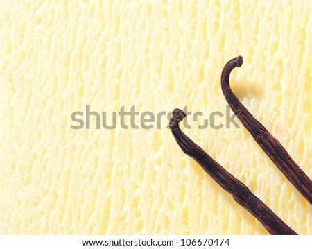 Closeup of a creamy icecream texture with two dried vanilla pods used as a flavouring during preparation