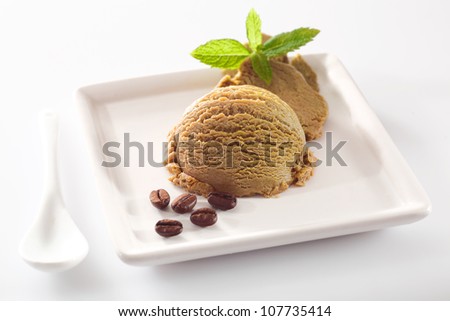 Serving of creamy aromatic coffee ice-cream on a square white porcelain plate with coffee bean garnish