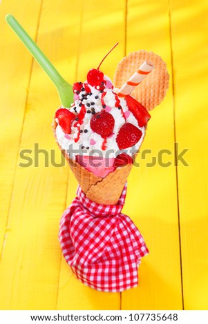 Gourmet ice-cream cone with ripe red strawberries and wafer biscuits wrapped in a checkered red and white napkin