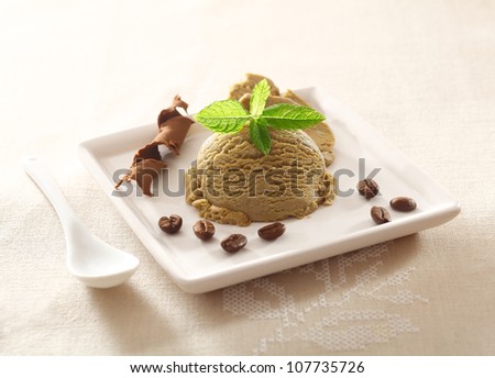 Serving of cool refreshing coffee ice-cream garnished with mint and chocolate and a scattering of roasted coffee beans