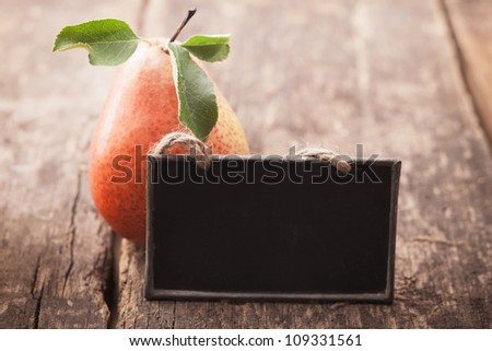 Fresh ripe red and yellow pear with a blank blackboard slate for your text on an old wooden table