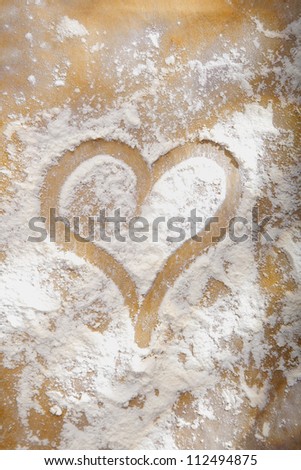 Heart drawn in sprinkled cooking flour symbolic of a love and enjoyment of baking or as a romantic symbol of love for an anniversary or Valentines
