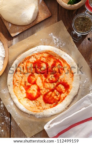 Raw pizza dough on brown wooden table. Preparing pizza for baking