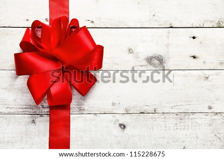Decorative red ribbon and bow on a background of white painted rustic boards with copyspace - stock photo