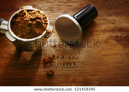 Freshly ground coffee beans in a metal filter on a wooden background with copyspace during preparation of a cup of aromatic filter coffee or espresso