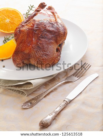 Delicious whole roasted chicken or duck served whole with sliced fresh oranges and a sprig of rosemary