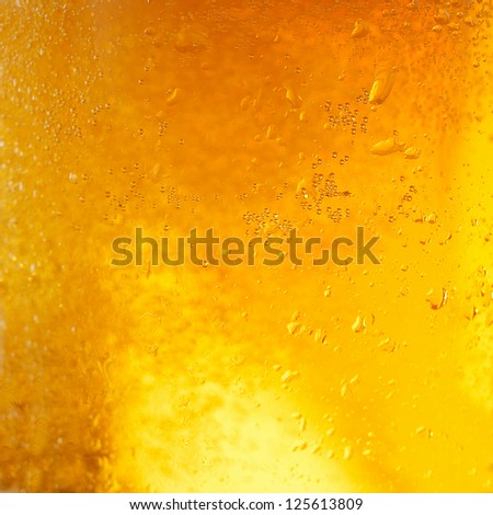 A background created from a closeup of cold light beer in a glass, with condensation droplets on the outside of the glass