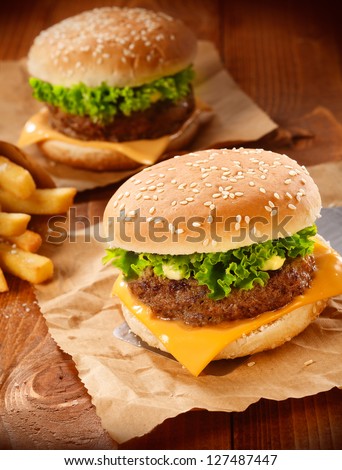 Two Hamburgers And French Fries On Brown Paper