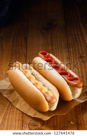 Two Hotdog, One With Ketchup, One With Mustard On Wooden Background