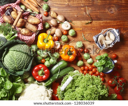 Overhead view of a delicious assortment of farm fresh vegetables, herbs and mushrooms spread out on a rustic wooden table