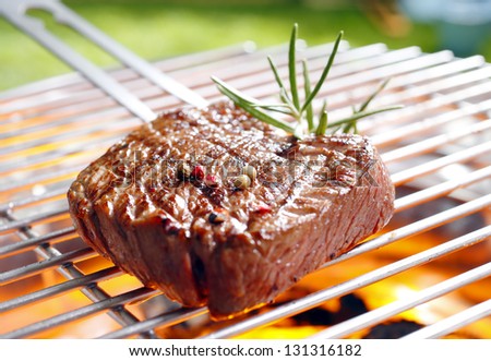 Grilled marinated steak on the grilling pan with open flames