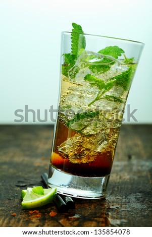 Iced mojito cocktail with rum and mint served in a tall glass on an old wooden table or bar counter
