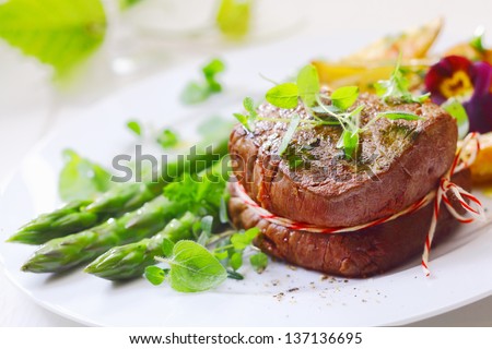 Medallion of roast fillet steak tied with string and served with fresh green asparagus tips and spears liberally garnished with fresh herbs