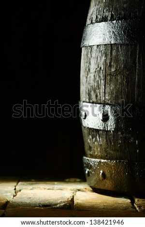 Old oak barrel standing upright on flagstones or old bricks with a dark background and copyspace conceptual of the aging and storing of wine, brandy or beer