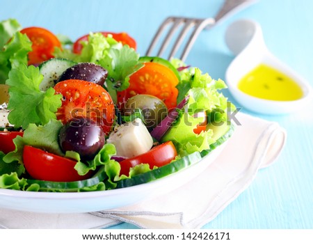 Healthy fresh Greek salad with olives and feta cheese nestling on a bed of crisp lettuce with tomato, closeup partial view of the dish