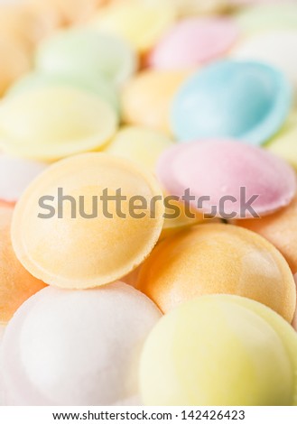 Macro vertical background texture made of many round candies in colorful pink, orange, yellow and green tones
