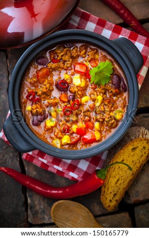 Overhead view of a pot of colourful, rich lentil and vegetable stew with peppers, corn, carrots and lentils in a ountry kitchen