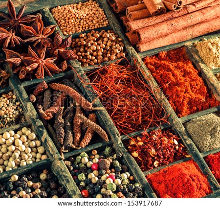 Variety of spices in an old printers tray with mixed peppercorns, red cayenne pepper, saffron, star anise, and cinnamon, closeup view