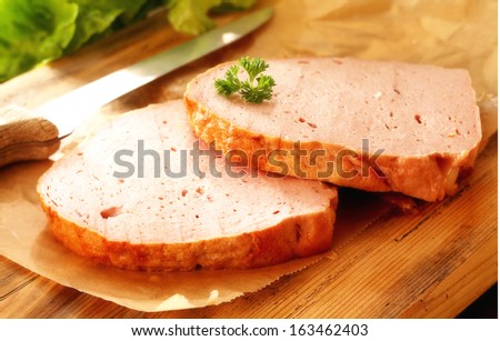 Sliced cold smoked German beef and pork loaf on a wooden board in the kitchen during preparation of a snack or sandwich