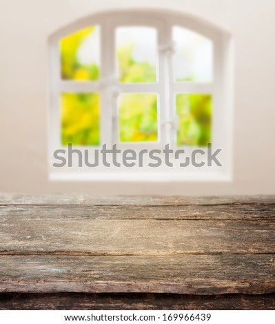 Old grunge table with a weathered rustic wooden top in front of a sunny cottage pane window in a country kitchen with space for your ingredients or product