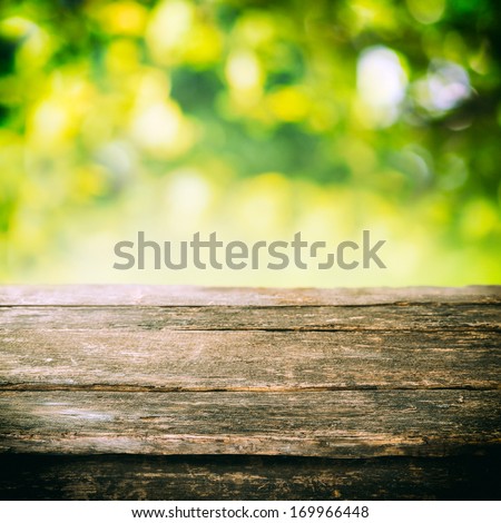 Empty Rustic Wooden Board Or Old Weathered Garden Table Top With Summer Greenery And Golden Sunlight In The Background