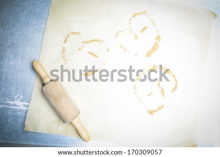 Rolling pin on oven paper with brezel print, overhead, aerial view with copyspace