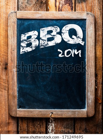 Old grunge BBQ advertising sign on an old school slate board with a distressed wooden frame and copyspace for your text mounted on wooden boards