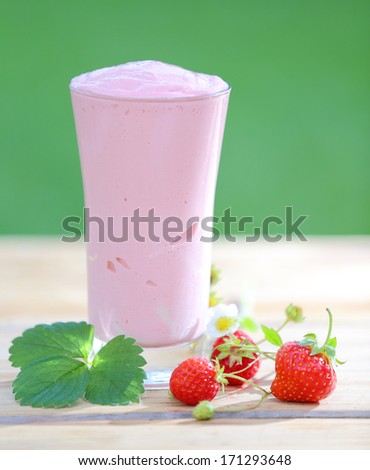 Tall glass of delicious strawberry smoothie blended with yoghurt or ice cream and fresh organic berries for a healthy drink full of vitamins and antioxidants