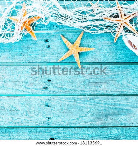 Pretty turquoise blue nautical background decorated with draped fishing net and starfish on painted rustic wooden boards with copyspace suitable as a card or party invitation, square format