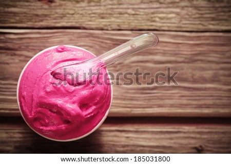 Refreshing tub of deep pink berry sorbet for a tasty cool summer treat , overhead view on an old weathered wooden table with copyspace