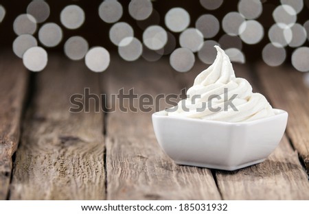 Ceramic dish of twirled delicious tangy lemon sorbet for a refreshing tropical summer dessert on an old rustic restaurant table with a bokeh of twinkling lights