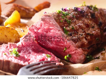 Portion of succulent rare roast beef carved for dinner with a close up view of the texture of the healthy lean red meat