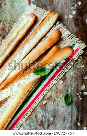 Pile of Italian grissini bread sticks, a long thin crisp bread baked from wheat dough served on a strip of hessian edged with the colors of the Italian national flag, high angle view