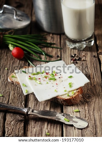 Preparing a delicious goats milk cheese sandwich topped with chopped fresh assorted herbs on a slice of rye bread in a rustic kitchen
