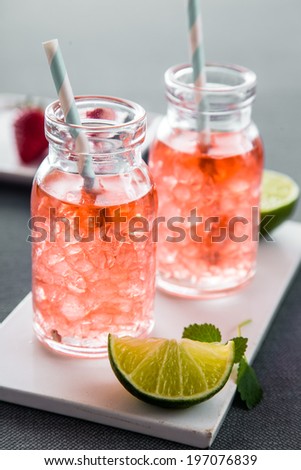 Fruity summer drinks with ice cubes in modern bottles, with fresh limes for sunny concepts