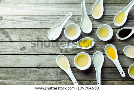 Topview of several soup spoons and sauce dishes filled with different colored oils
