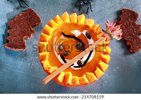 Halloween Pumpkin Soup Served in Half a Pumpkin with Bat Shaped Crouton Toasts and Broomstick Bread Stick from Above
