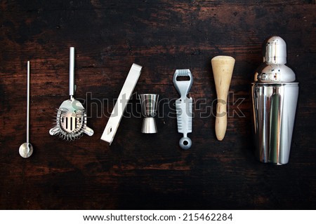 Set of bar or pub accessories with a martini cocktail shaker arranged in a neat line on a black background