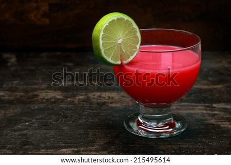 Bloody Mary tomato cocktail garnished with lemon standing on an old wooden bar counter against a dark background with copyspace