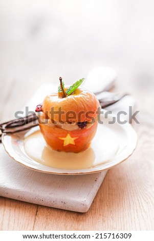 Stuffed Halloween apple dessert with a gaping mouth filled with teeth and a golden star garnished with a fresh mint leaf and served on a white plate with copyspace for your greeting or invitation