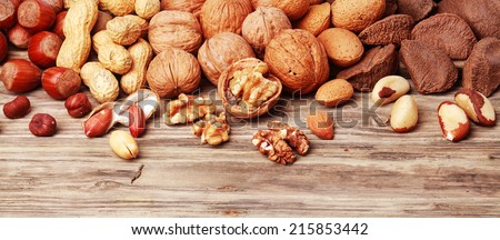 Variety of shelled and whole nuts in a horizontal banner including almonds, hazelnuts, brazil nuts, peanuts and walnuts on a rustic wooden background with copyspace