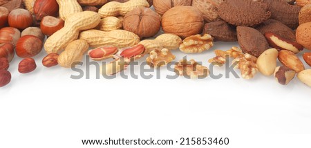 Mixed whole and shelled nuts in a horizontal banner including hazelnuts, brazil nuts, peanuts or groundnuts and walnuts on white with copyspace below