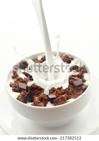 Pouring milk with a splash of droplets into a bowl of crunchy choc chip breakfast cereal rich in wheat, oats and bran for an energising low-CI start to the day