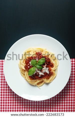Gourmet Italian Pasta Food on White Round Plate Placed Between Red White Checked and Black Background.