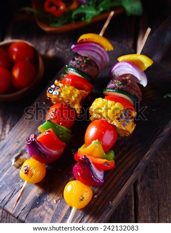 Colorful vegan vegetable skewers with fresh roasted or grilled sweet peppers, onion, mushroom, corn, eggplant and cherry tomatoes, view from above on a wooden board
